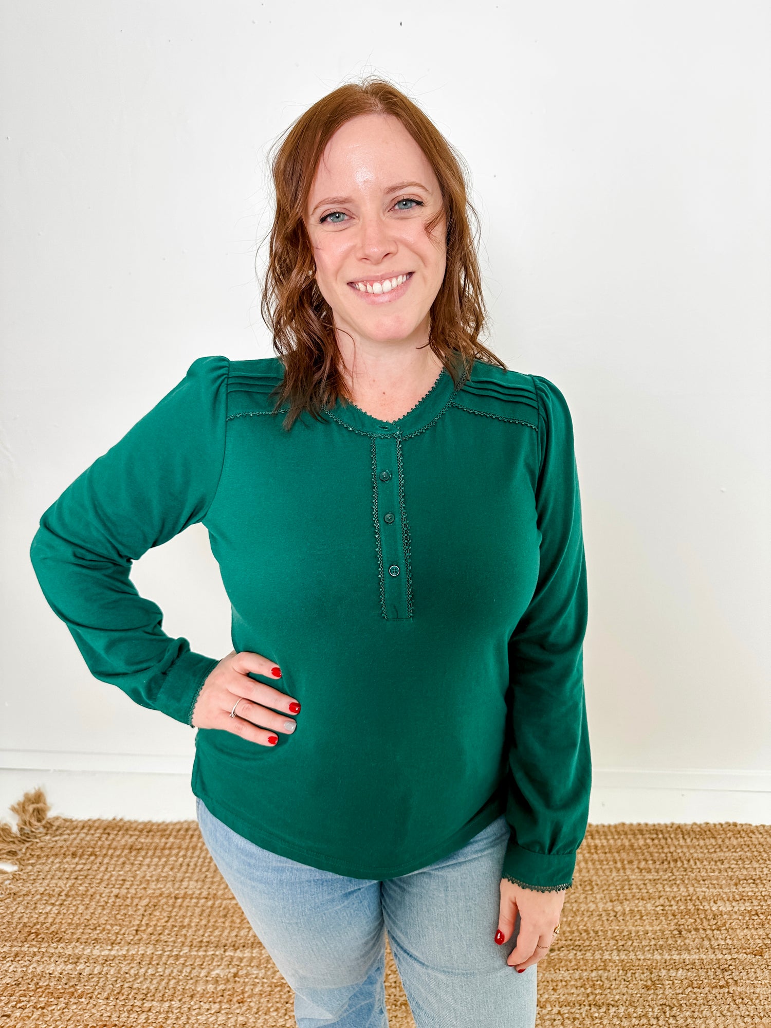 Women's knit blouse with lace detail, made from 100% cotton jersey surplus fabric. Available in Evergreen. Features a collarless band neckline, matching button-front placket, delicate knit lace on shoulders, collar, cuffs, and placket, keyhole buttoned cuffs, and side slits. Medium-weight fabric with light stretch for a straight fit. Available in sizes XS-3X.