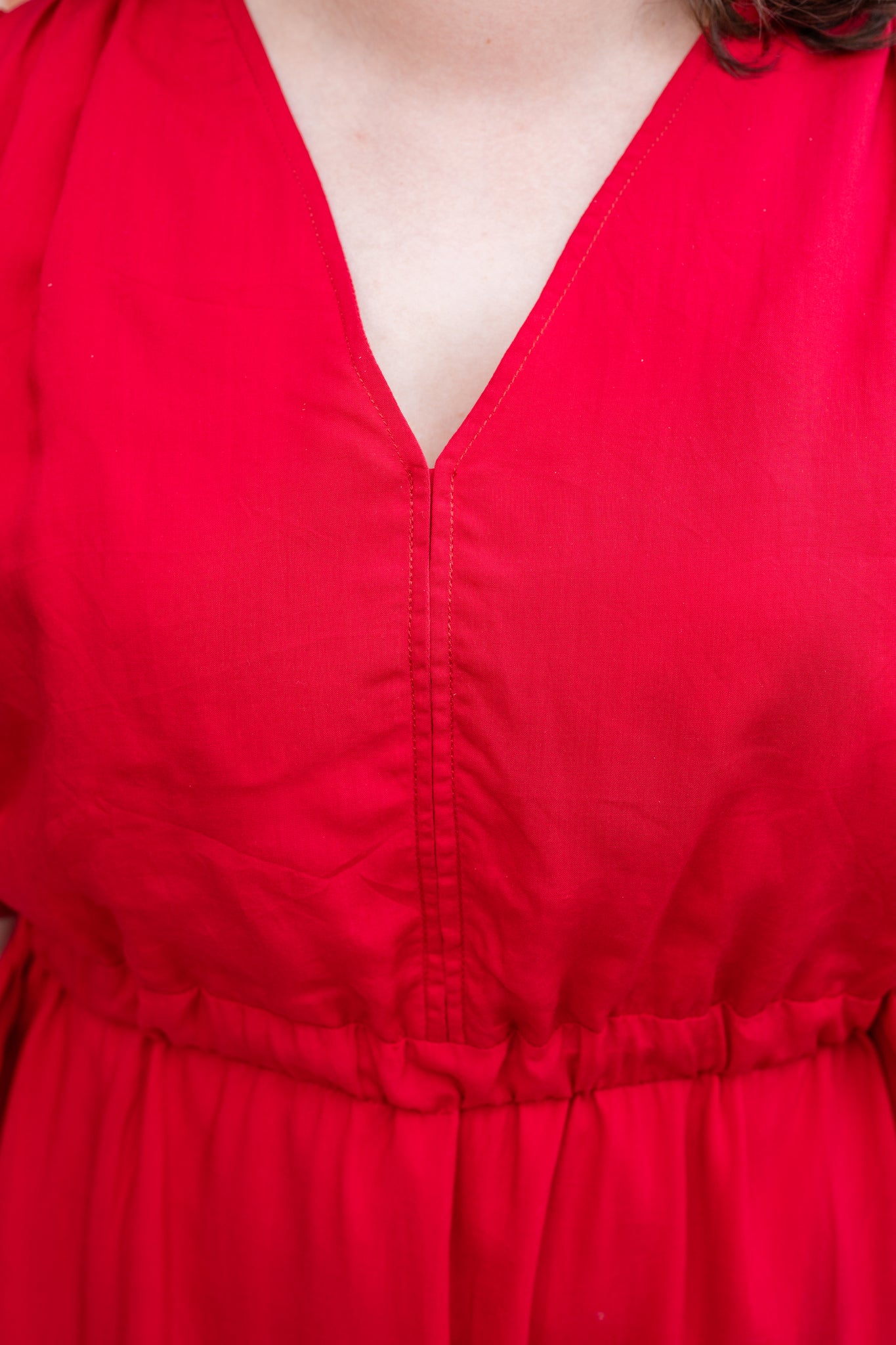 Elegant midi-length dress in surplus 100% cotton with puff sleeves and a unique V-neckline. Features ruching along the bodice, shoulders, and skirt, plus drawstring bows at the waist for a flattering fit. Designed with hidden side pockets, elbow-length keyhole cuff sleeves, and a box-pleated hem. Finished with French seams and a hidden decorative placket.