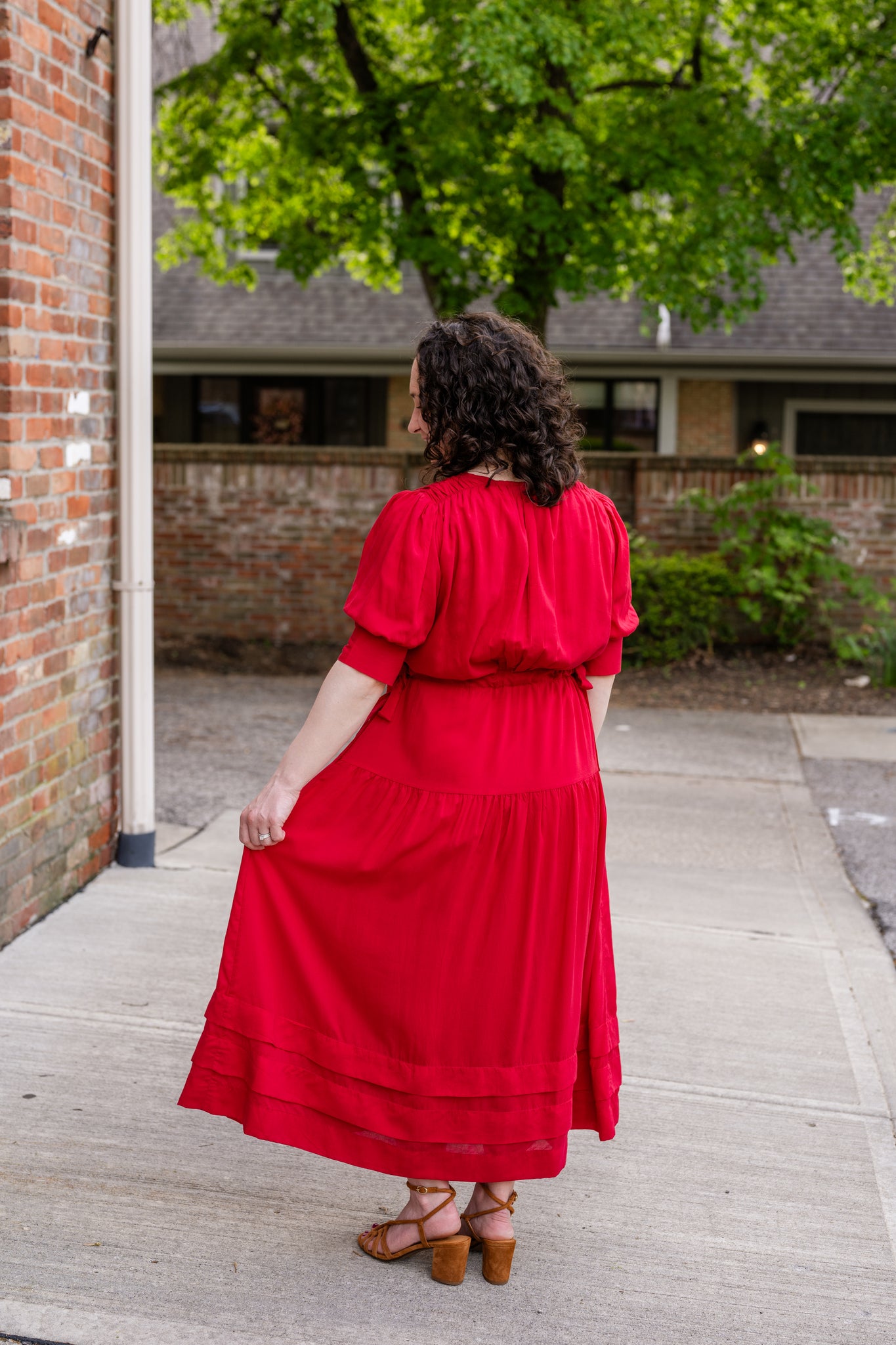 Elegant midi-length dress in surplus 100% cotton with puff sleeves and a unique V-neckline. Features ruching along the bodice, shoulders, and skirt, plus drawstring bows at the waist for a flattering fit. Designed with hidden side pockets, elbow-length keyhole cuff sleeves, and a box-pleated hem. Finished with French seams and a hidden decorative placket.