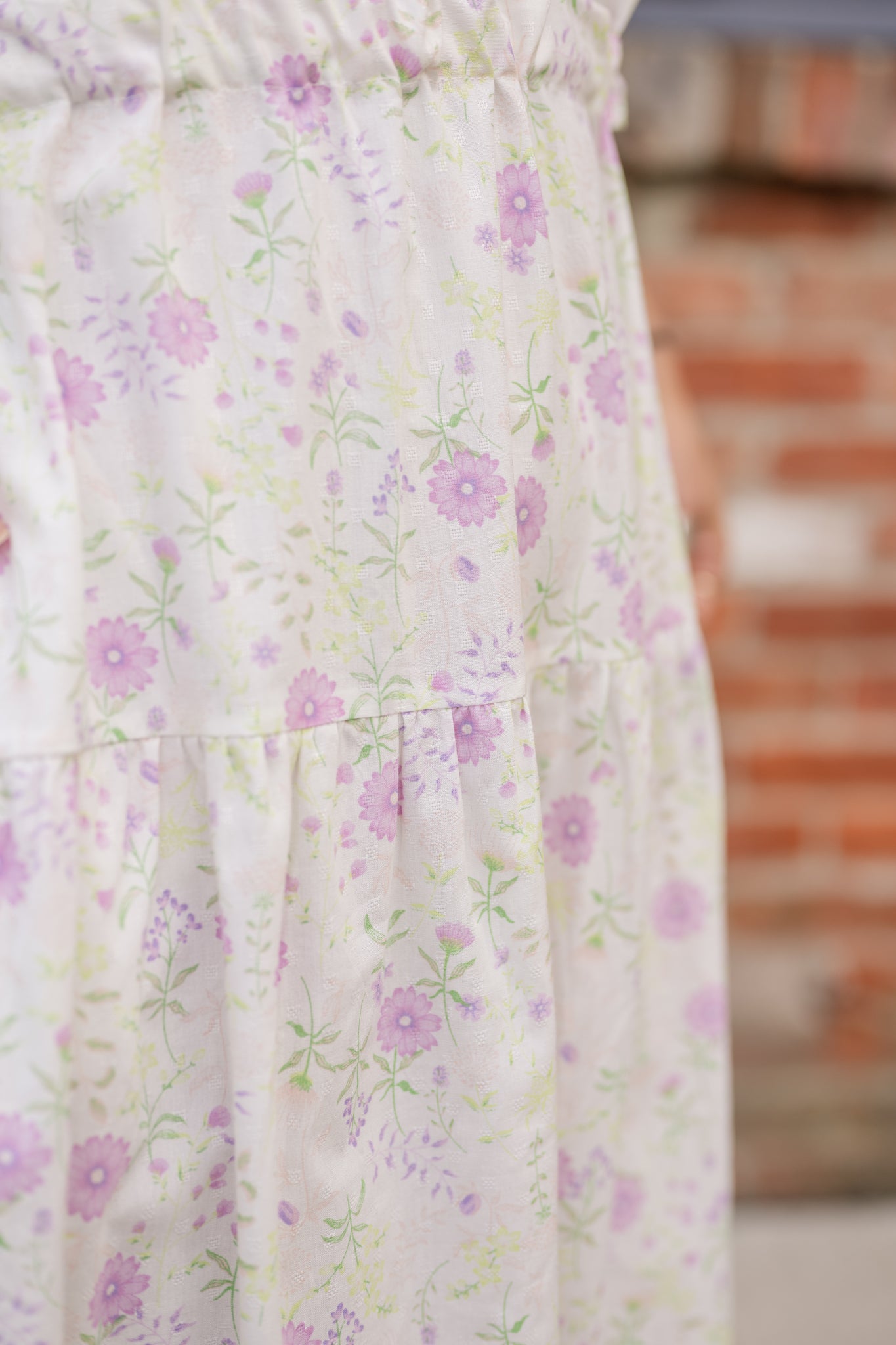 Elegant midi-length dress in surplus 100% cotton with puff sleeves and a unique V-neckline. Features ruching along the bodice, shoulders, and skirt, plus drawstring bows at the waist for a flattering fit. Designed with hidden side pockets, elbow-length keyhole cuff sleeves, and a box-pleated hem. Finished with French seams and a hidden decorative placket.