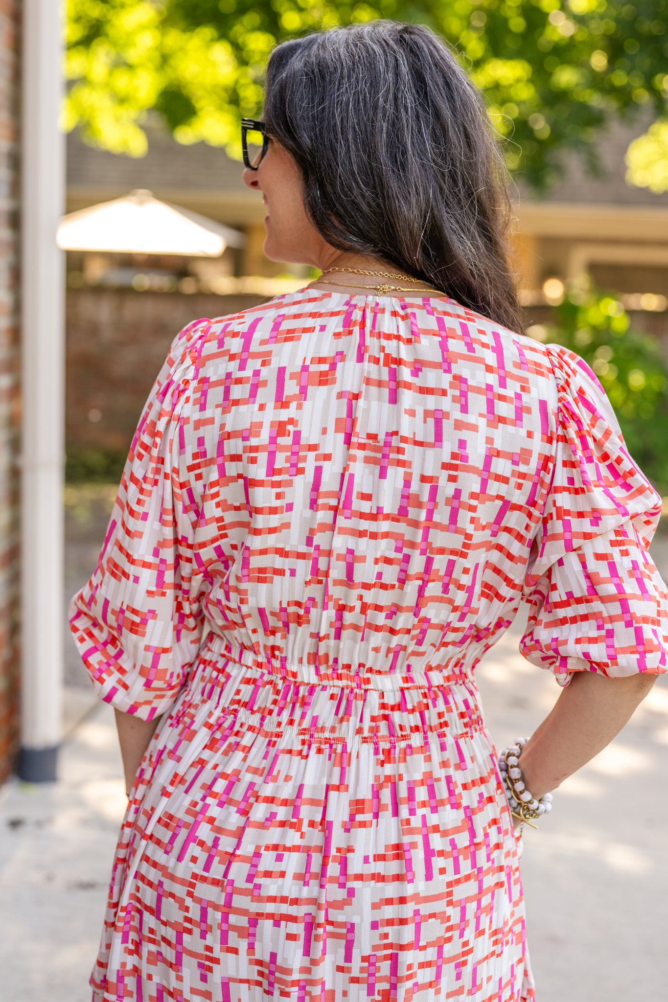 Chic midi dress made from 100% woven viscose surplus fabric, featuring a flattering V-neck with hook-and-eye closures. Designed with a smocked waist for a contoured fit, side slant pockets for convenience, and a pintuck hem between tiers for added texture. Pullover styling with elastic-cuff 3/4 length sleeves, subtle shoulder gathers, and delicate sleeve detailing. A versatile and breathable dress perfect for effortless style.