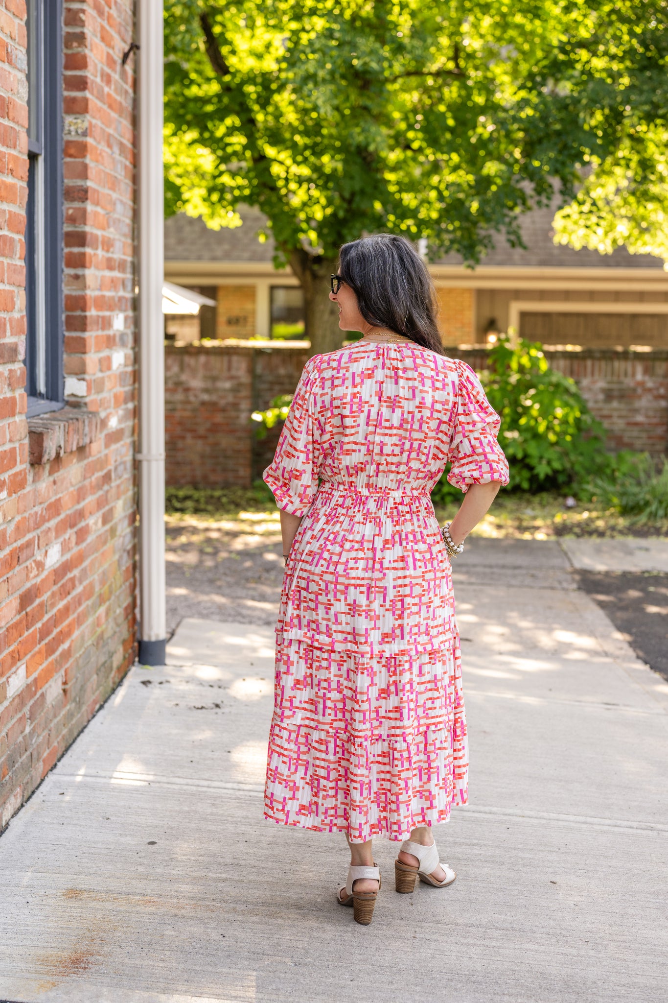 Chic midi dress made from 100% woven viscose surplus fabric, featuring a flattering V-neck with hook-and-eye closures. Designed with a smocked waist for a contoured fit, side slant pockets for convenience, and a pintuck hem between tiers for added texture. Pullover styling with elastic-cuff 3/4 length sleeves, subtle shoulder gathers, and delicate sleeve detailing. A versatile and breathable dress perfect for effortless style.