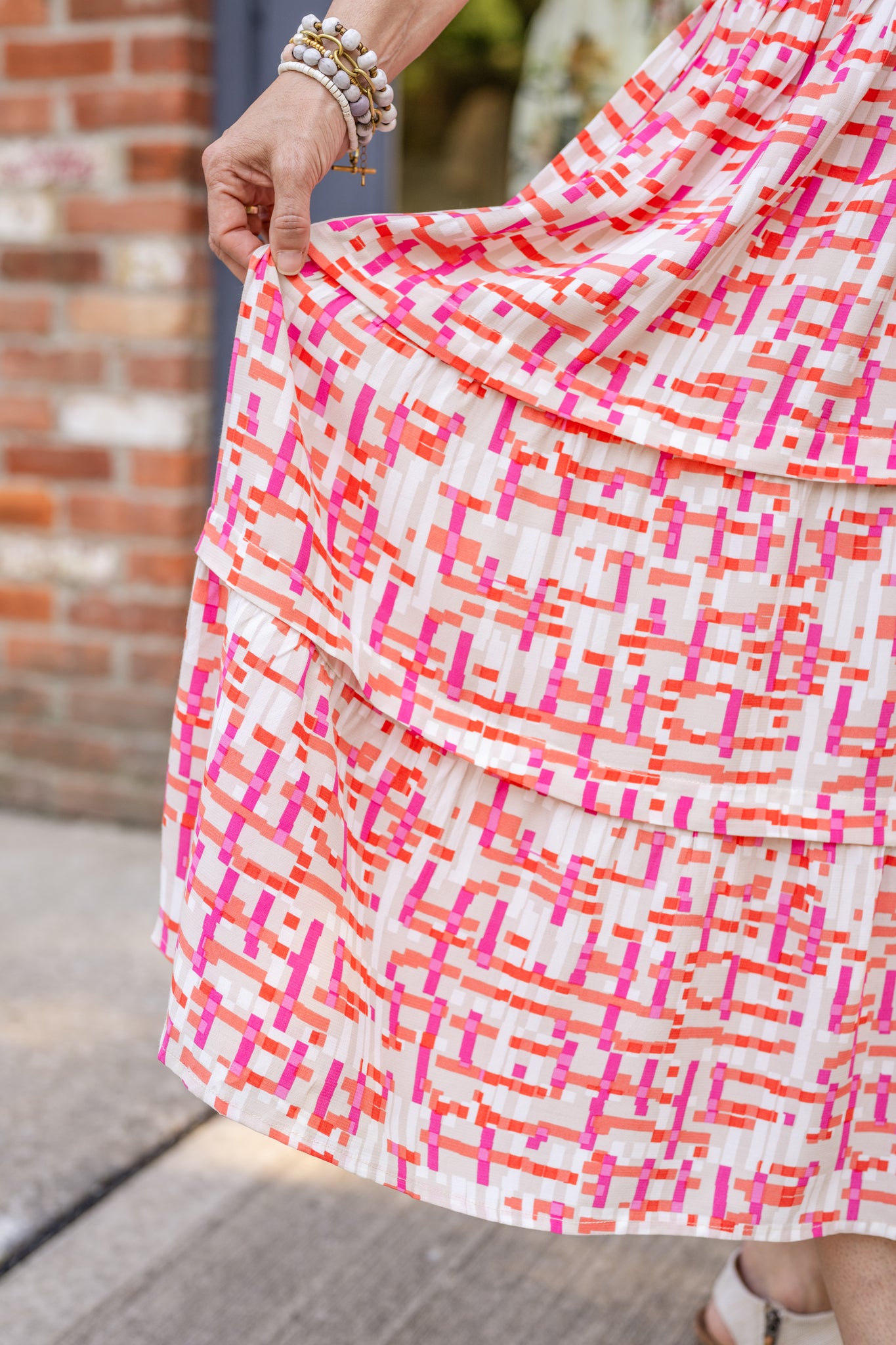 Chic midi dress made from 100% woven viscose surplus fabric, featuring a flattering V-neck with hook-and-eye closures. Designed with a smocked waist for a contoured fit, side slant pockets for convenience, and a pintuck hem between tiers for added texture. Pullover styling with elastic-cuff 3/4 length sleeves, subtle shoulder gathers, and delicate sleeve detailing. A versatile and breathable dress perfect for effortless style.