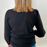 Women's knit blouse with lace detail, made from 100% cotton jersey surplus fabric. Available in black. Features a collarless band neckline, matching button-front placket, delicate knit lace on shoulders, collar, cuffs, and placket, keyhole buttoned cuffs, and side slits. Medium-weight fabric with light stretch for a straight fit. Available in sizes XS-3X.