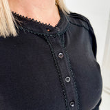 Women's knit blouse with lace detail, made from 100% cotton jersey surplus fabric. Available in black. Features a collarless band neckline, matching button-front placket, delicate knit lace on shoulders, collar, cuffs, and placket, keyhole buttoned cuffs, and side slits. Medium-weight fabric with light stretch for a straight fit. Available in sizes XS-3X.