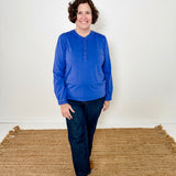 Women's knit blouse with lace detail, made from 100% cotton jersey surplus fabric. Available in sapphire. Features a collarless band neckline, matching button-front placket, delicate knit lace on shoulders, collar, cuffs, and placket, keyhole buttoned cuffs, and side slits. Medium-weight fabric with light stretch for a straight fit. Available in sizes XS-3X.