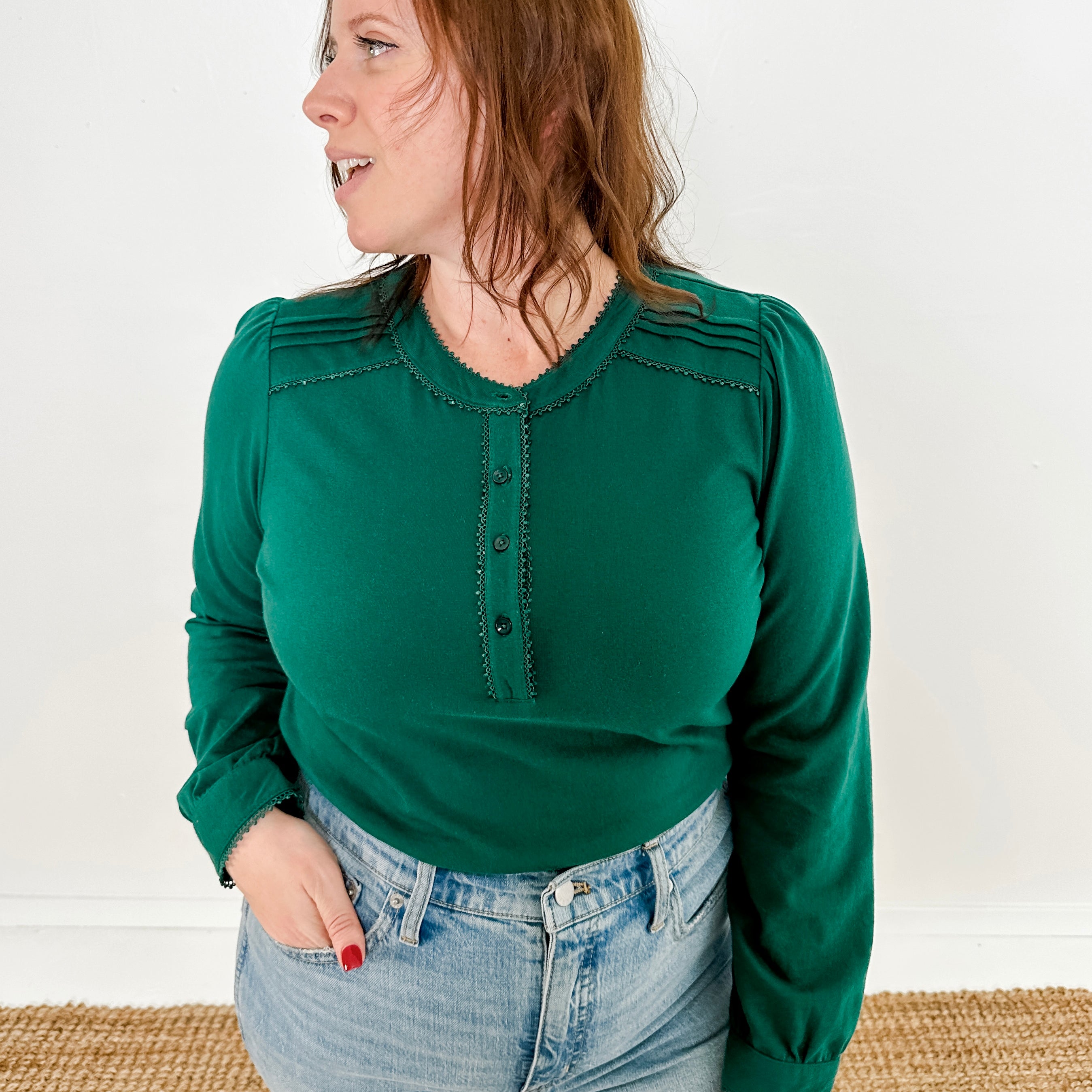 Women's knit blouse with lace detail, made from 100% cotton jersey surplus fabric. Available in Evergreen. Features a collarless band neckline, matching button-front placket, delicate knit lace on shoulders, collar, cuffs, and placket, keyhole buttoned cuffs, and side slits. Medium-weight fabric with light stretch for a straight fit. Available in sizes XS-3X. 