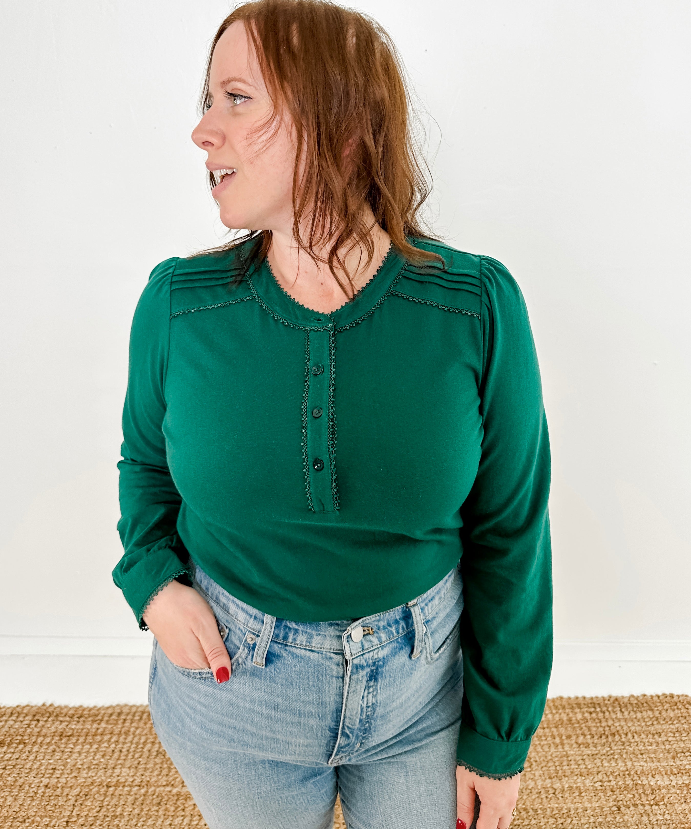 Women's knit blouse with lace detail, made from 100% cotton jersey surplus fabric. Available in Evergreen. Features a collarless band neckline, matching button-front placket, delicate knit lace on shoulders, collar, cuffs, and placket, keyhole buttoned cuffs, and side slits. Medium-weight fabric with light stretch for a straight fit. Available in sizes XS-3X. 