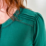 Women's knit blouse with lace detail, made from 100% cotton jersey surplus fabric. Available in Evergreen. Features a collarless band neckline, matching button-front placket, delicate knit lace on shoulders, collar, cuffs, and placket, keyhole buttoned cuffs, and side slits. Medium-weight fabric with light stretch for a straight fit. Available in sizes XS-3X. 