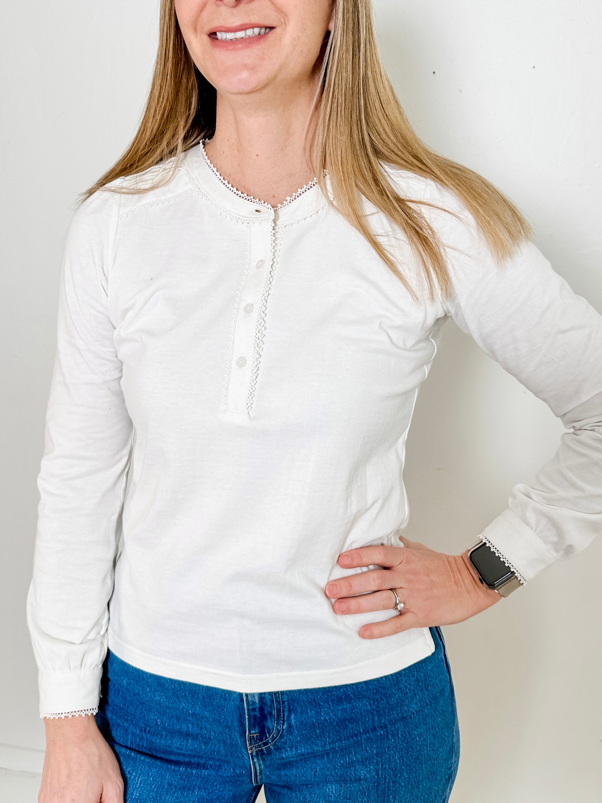 Women's knit blouse with lace detail, made from 100% cotton jersey surplus fabric. Available in white. Features a collarless band neckline, matching button-front placket, delicate knit lace on shoulders, collar, cuffs, and placket, keyhole buttoned cuffs, and side slits. Medium-weight fabric with light stretch for a straight fit. Available in sizes XS-3X. 