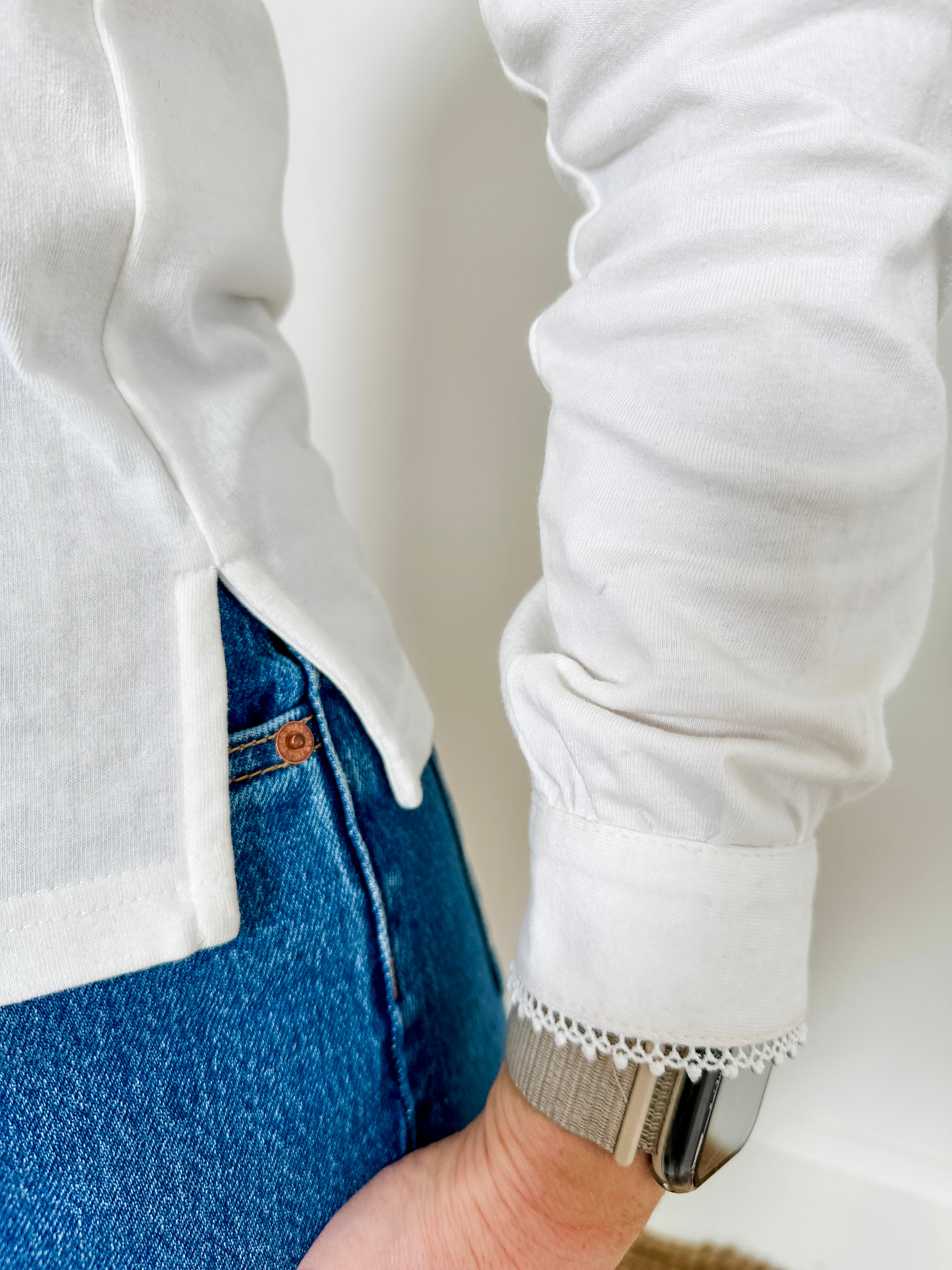 Women's knit blouse with lace detail, made from 100% cotton jersey surplus fabric. Available in white. Features a collarless band neckline, matching button-front placket, delicate knit lace on shoulders, collar, cuffs, and placket, keyhole buttoned cuffs, and side slits. Medium-weight fabric with light stretch for a straight fit. Available in sizes XS-3X. 