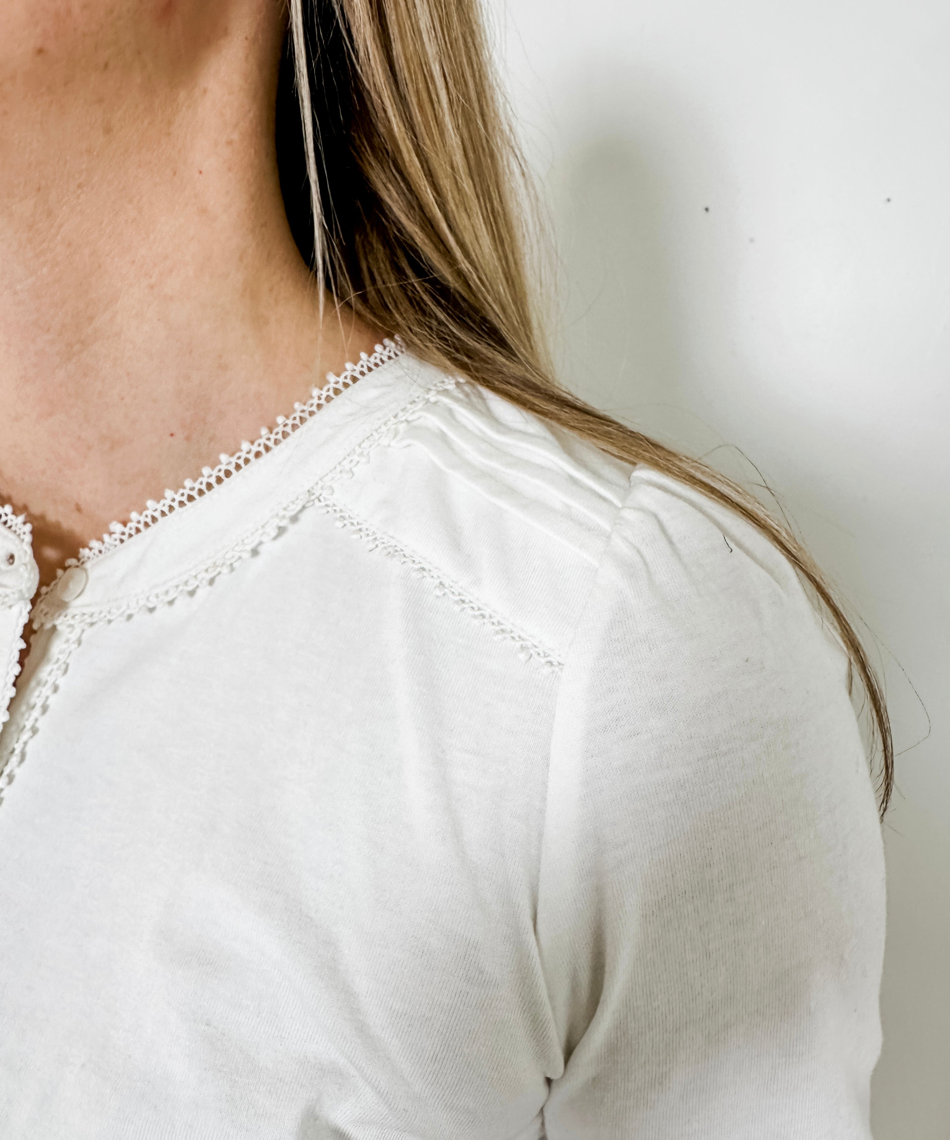 Women's knit blouse with lace detail, made from 100% cotton jersey surplus fabric. Available in white. Features a collarless band neckline, matching button-front placket, delicate knit lace on shoulders, collar, cuffs, and placket, keyhole buttoned cuffs, and side slits. Medium-weight fabric with light stretch for a straight fit. Available in sizes XS-3X. 