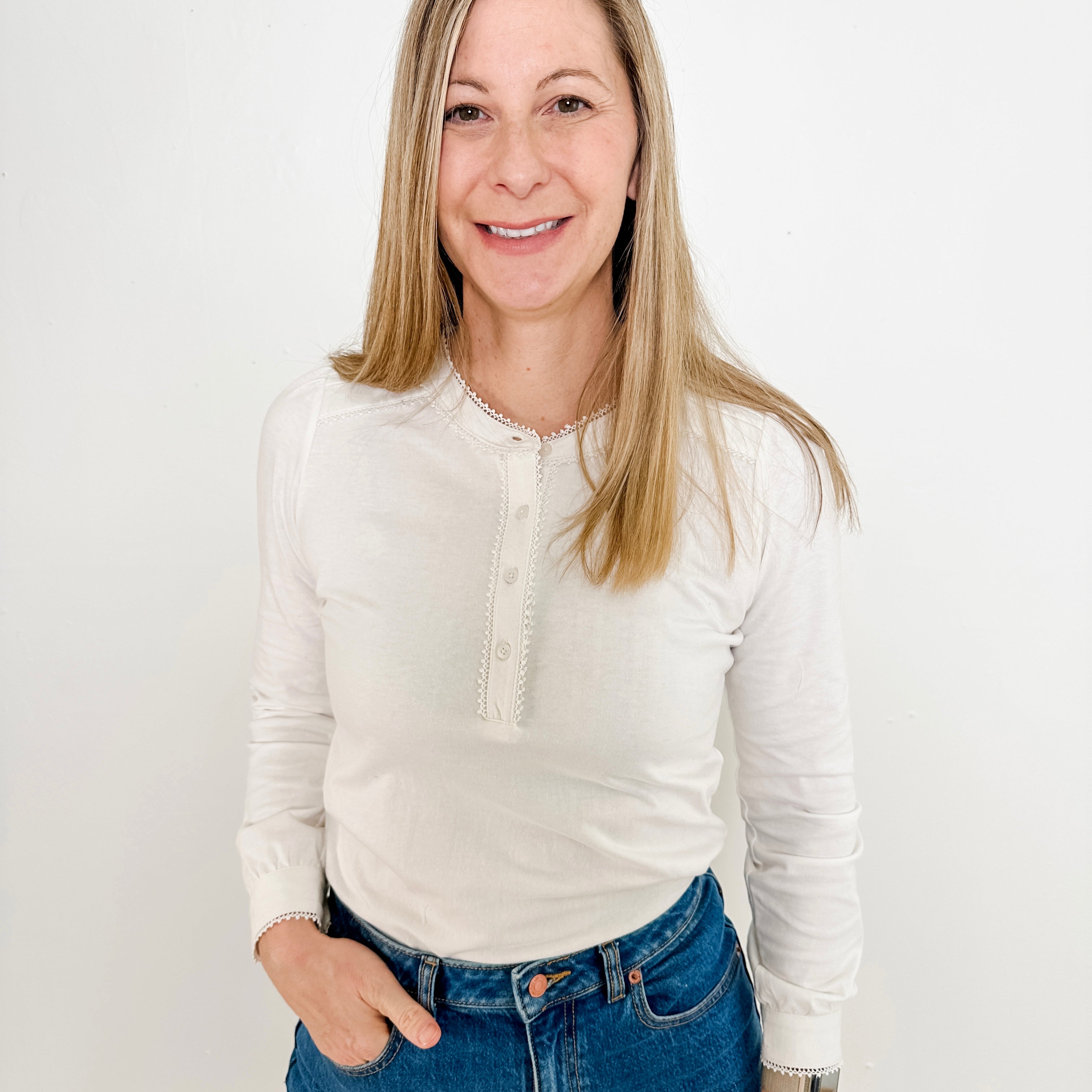 Women's knit blouse with lace detail, made from 100% cotton jersey surplus fabric. Available in white. Features a collarless band neckline, matching button-front placket, delicate knit lace on shoulders, collar, cuffs, and placket, keyhole buttoned cuffs, and side slits. Medium-weight fabric with light stretch for a straight fit. Available in sizes XS-3X. 