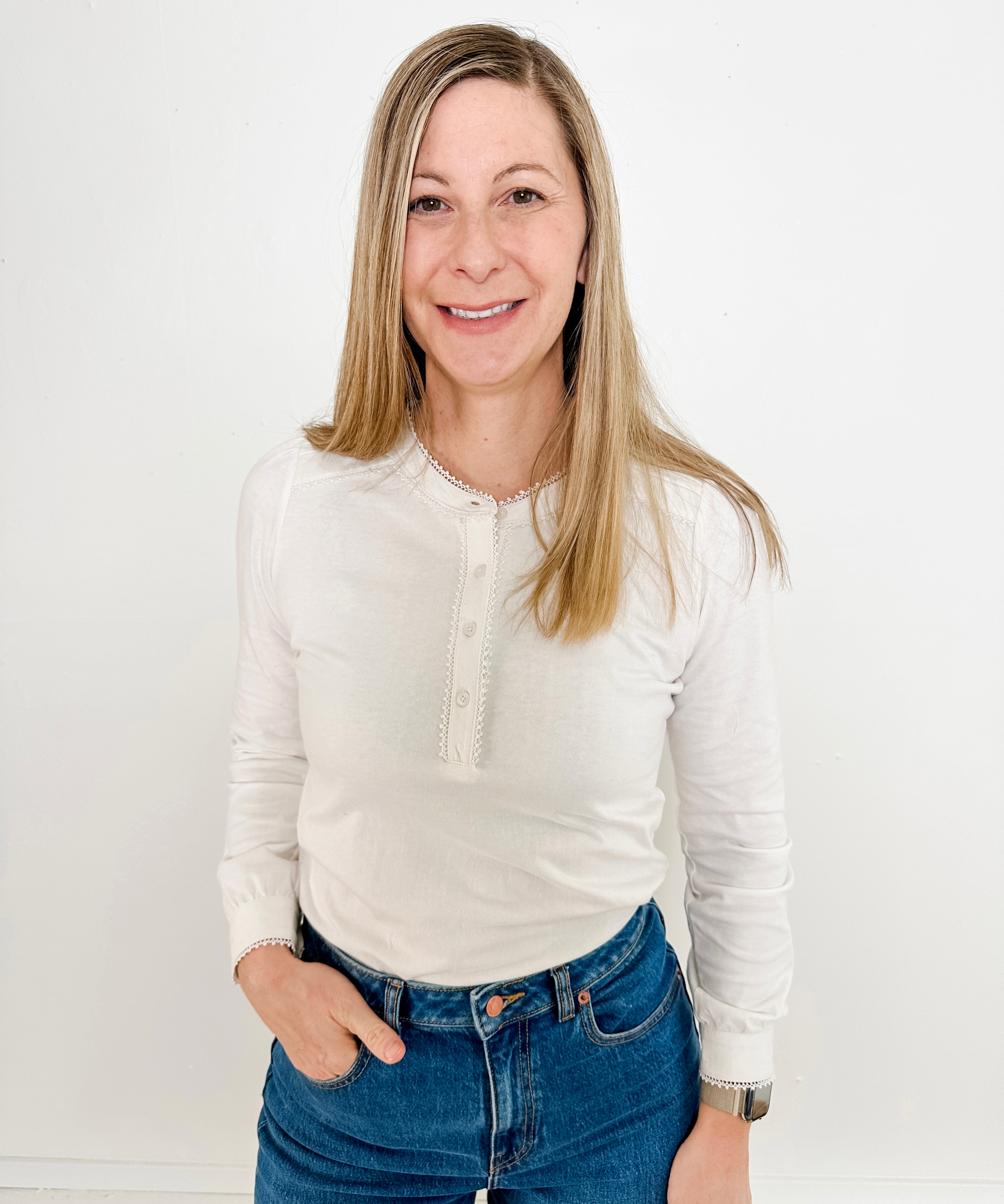 Women's knit blouse with lace detail, made from 100% cotton jersey surplus fabric. Available in white. Features a collarless band neckline, matching button-front placket, delicate knit lace on shoulders, collar, cuffs, and placket, keyhole buttoned cuffs, and side slits. Medium-weight fabric with light stretch for a straight fit. Available in sizes XS-3X. 