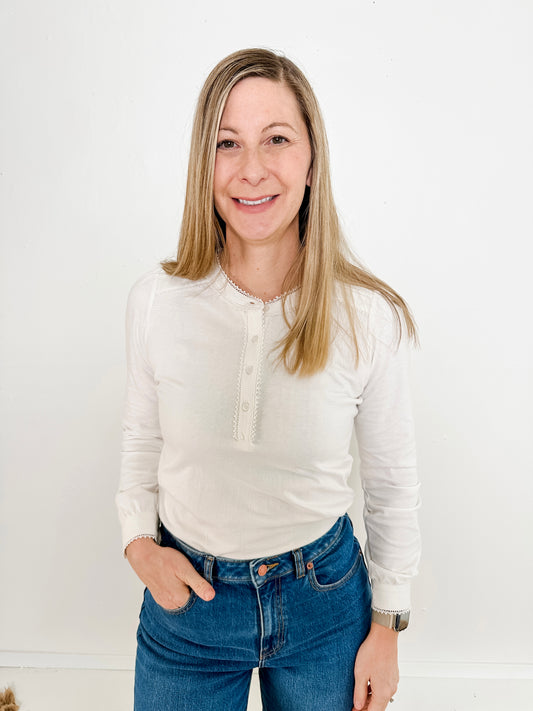 Women's knit blouse with lace detail, made from 100% cotton jersey surplus fabric. Available in white. Features a collarless band neckline, matching button-front placket, delicate knit lace on shoulders, collar, cuffs, and placket, keyhole buttoned cuffs, and side slits. Medium-weight fabric with light stretch for a straight fit. Available in sizes XS-3X.