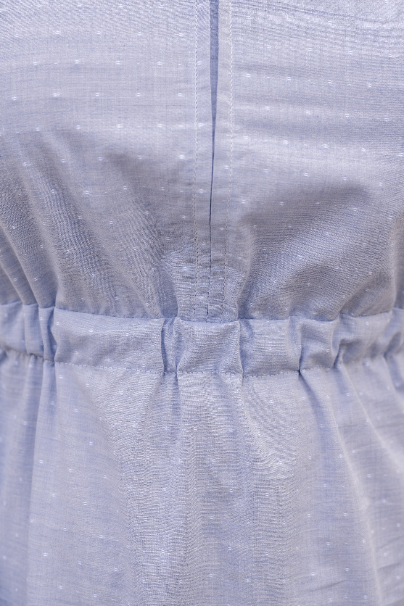 Elegant midi-length dress in surplus 100% cotton with puff sleeves and a unique V-neckline. Features ruching along the bodice, shoulders, and skirt, plus drawstring bows at the waist for a flattering fit. Designed with hidden side pockets, elbow-length keyhole cuff sleeves, and a box-pleated hem. Finished with French seams and a hidden decorative placket.