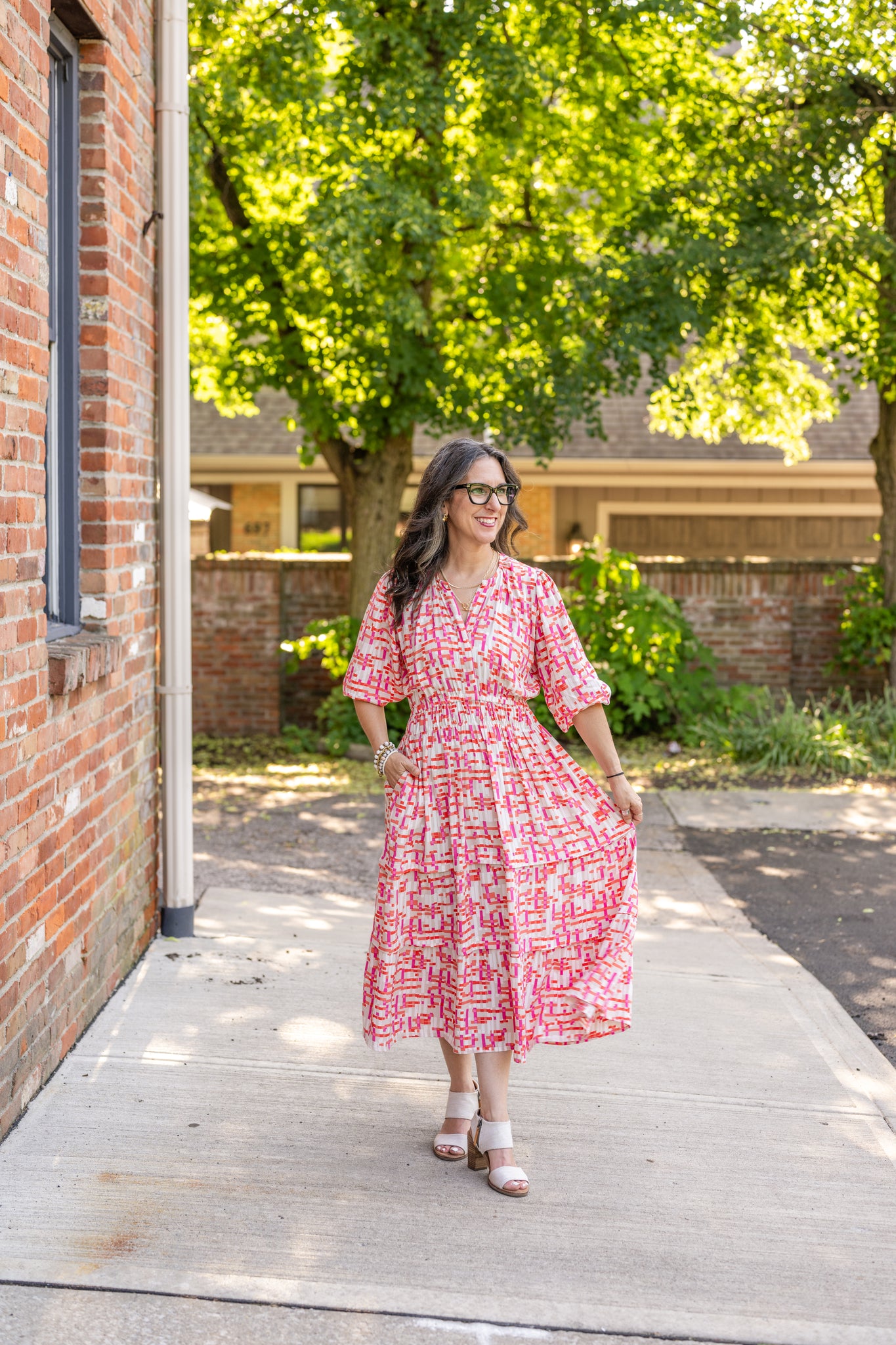 Chic midi dress made from 100% woven viscose surplus fabric, featuring a flattering V-neck with hook-and-eye closures. Designed with a smocked waist for a contoured fit, side slant pockets for convenience, and a pintuck hem between tiers for added texture. Pullover styling with elastic-cuff 3/4 length sleeves, subtle shoulder gathers, and delicate sleeve detailing. A versatile and breathable dress perfect for effortless style.